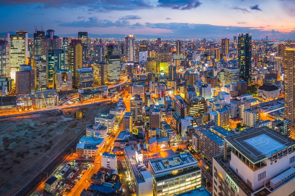 The glittering lights, neon night, soaring skyscrapers and zooming highways of the futuristic crowded cityscape of central Osaka, Japan.
