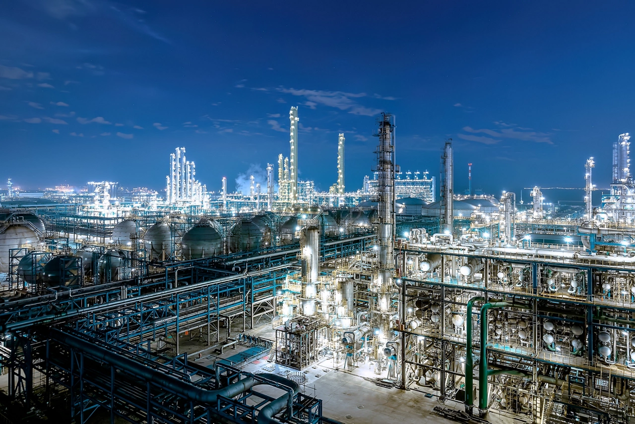 Industrial chemical plant equipment and pipelines at night view.