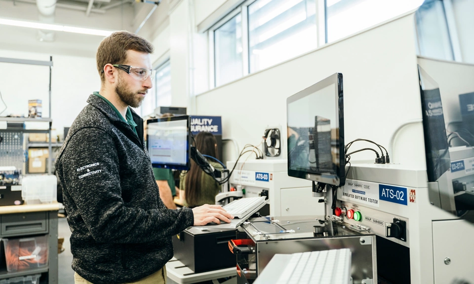 Engineer operating a hardware-in-the-loop (HIL) test system based on NI PXI hardware and NI software to validate embedded control algorithms.