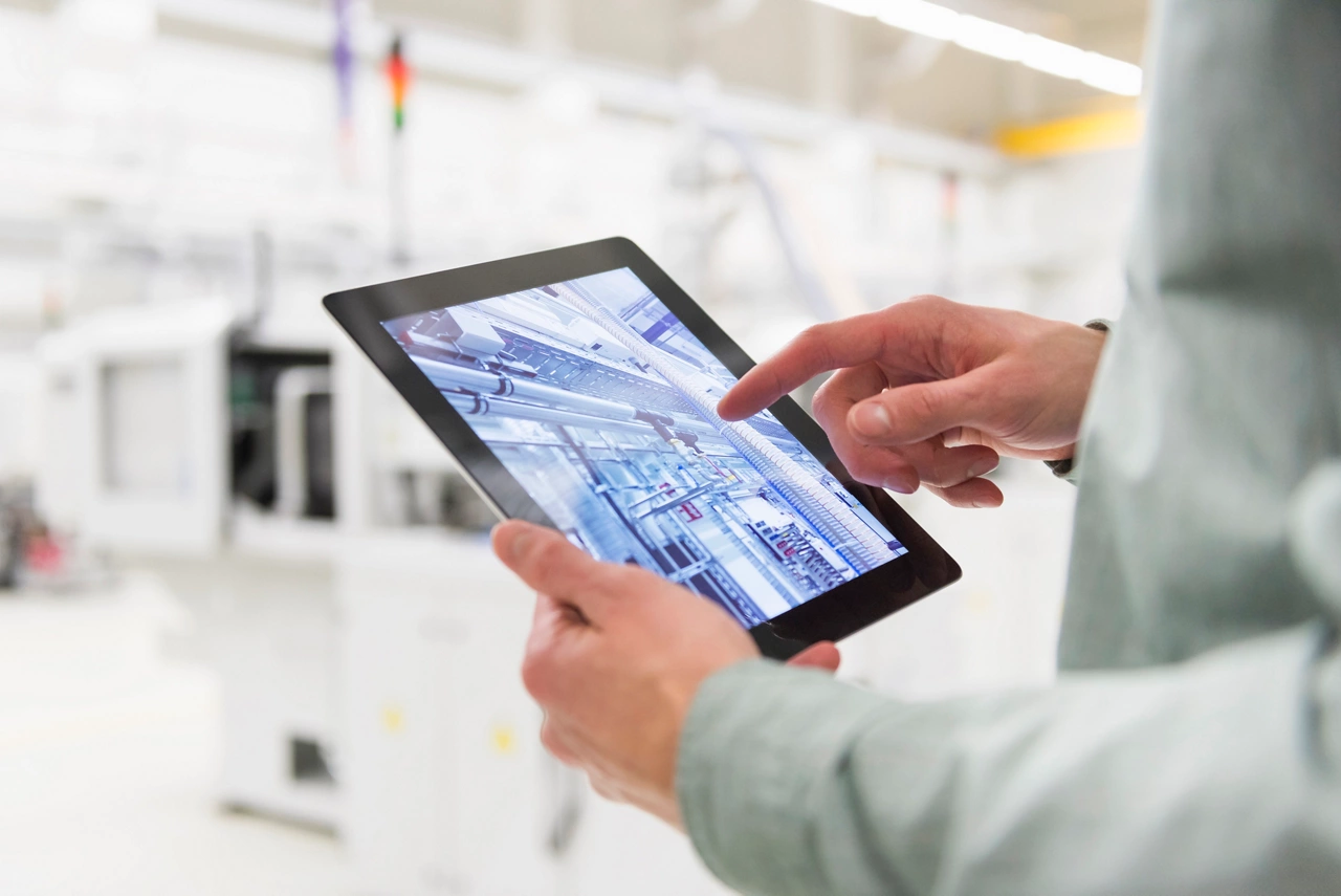 Male worker using digital tablet at tool manufacturing plant, focus on hands