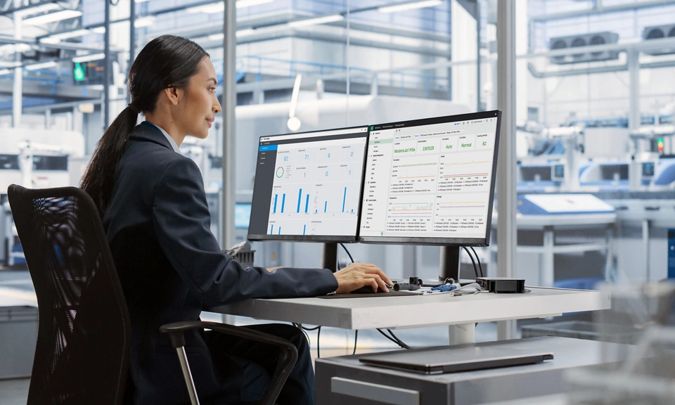 Engineer in a modern lab analyzing test data with NI SystemLink software dashboards, to monitor health of connected test systems, teams, and data.