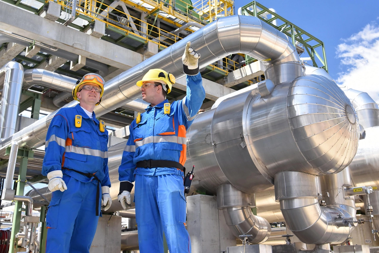 teamwork: group of industrial workers in a refinery - oil processing equipment and machinery