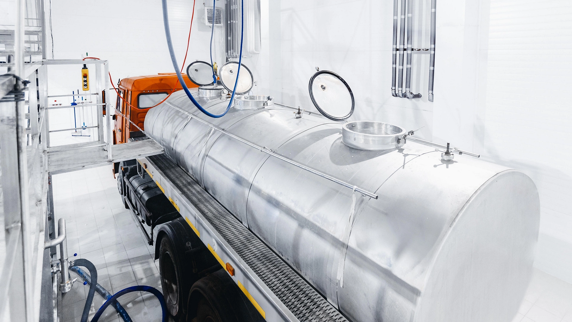 Milk tanker truck pumps products into steel storage tanks, dairy factory industry.